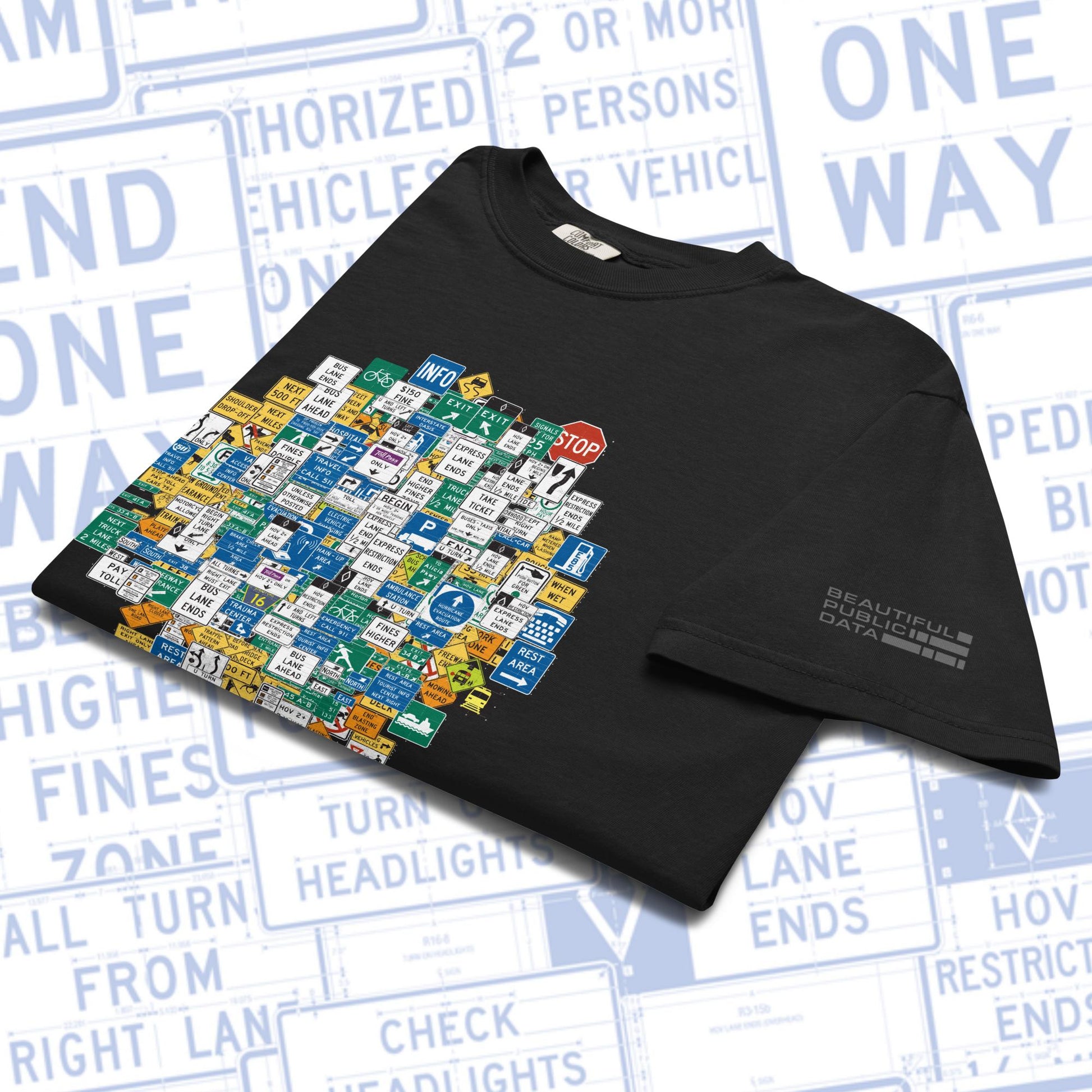 Black t-shirt with colorful road sign graphic on a background of road signs.